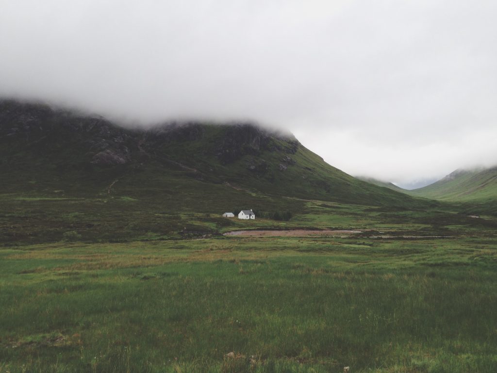 A wide Highland valley with a white crofthouse in the distance, low cloud covers the hills, 
Copyright Antoine Fabre @antoinefbr